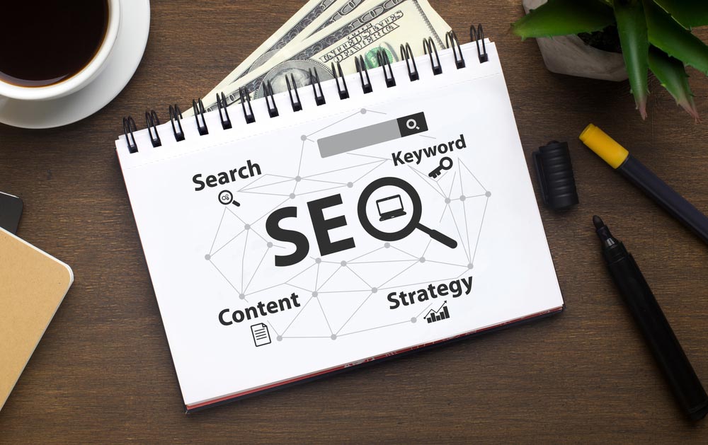 Opened Notebook With Seo-Optimization Scheme Lying Over Brown Office Table Background